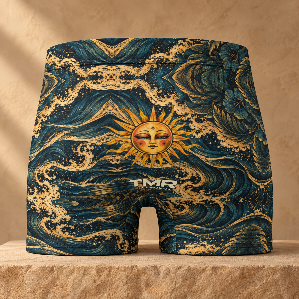 Calzoncillos bóxer Sol de Medianoche — TMR by Tamar Melián 1 Vista trasera del bóxer Sol de Medianoche TMR, con sol dorado y firma TMR by Tamar Melián sobre estampado azul petróleo.