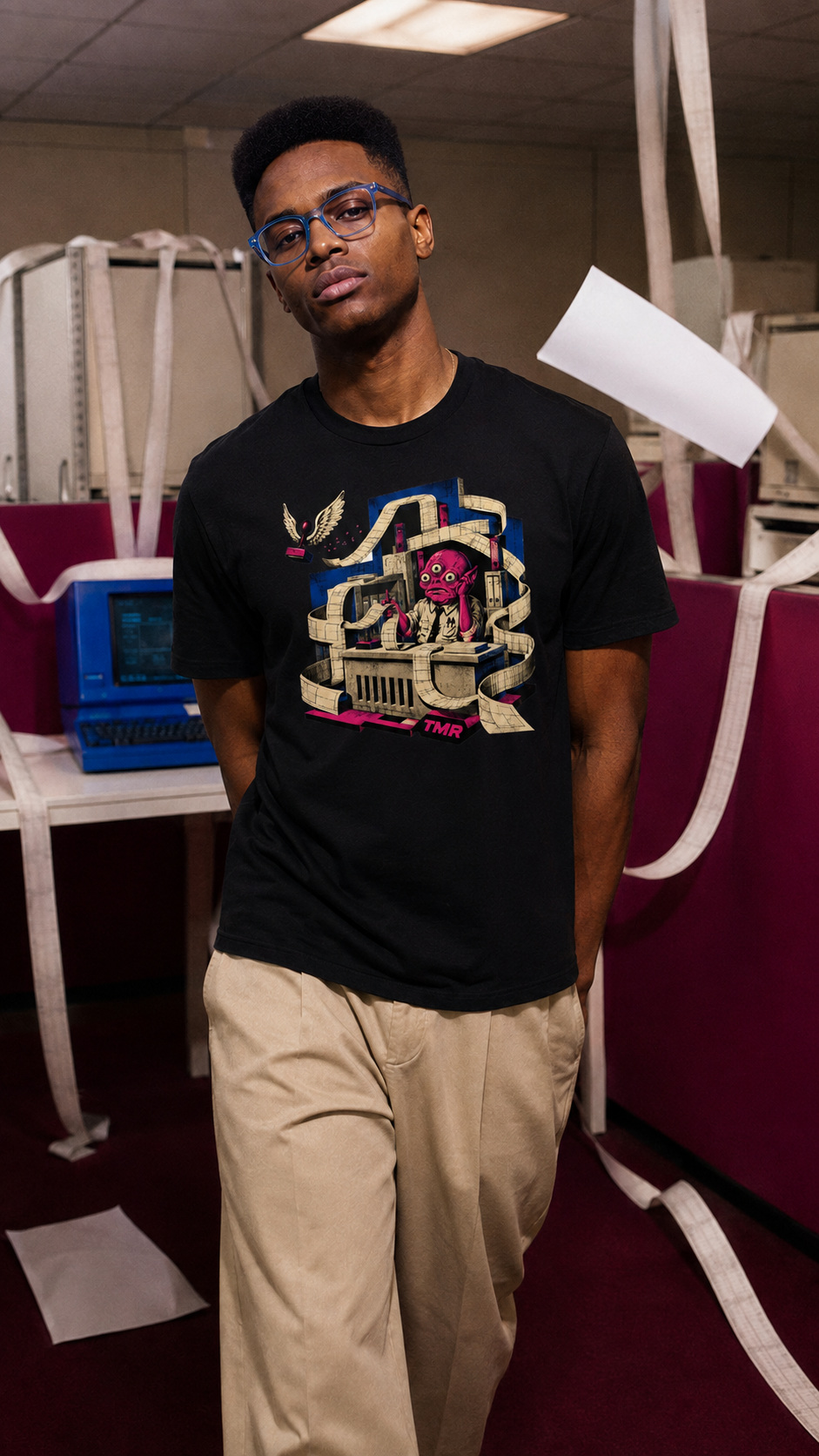 Buró del caos — Camiseta 3 Mockup digital de un hombre con la camiseta negra Buró del caos en una oficina con papeles a su alrededor.