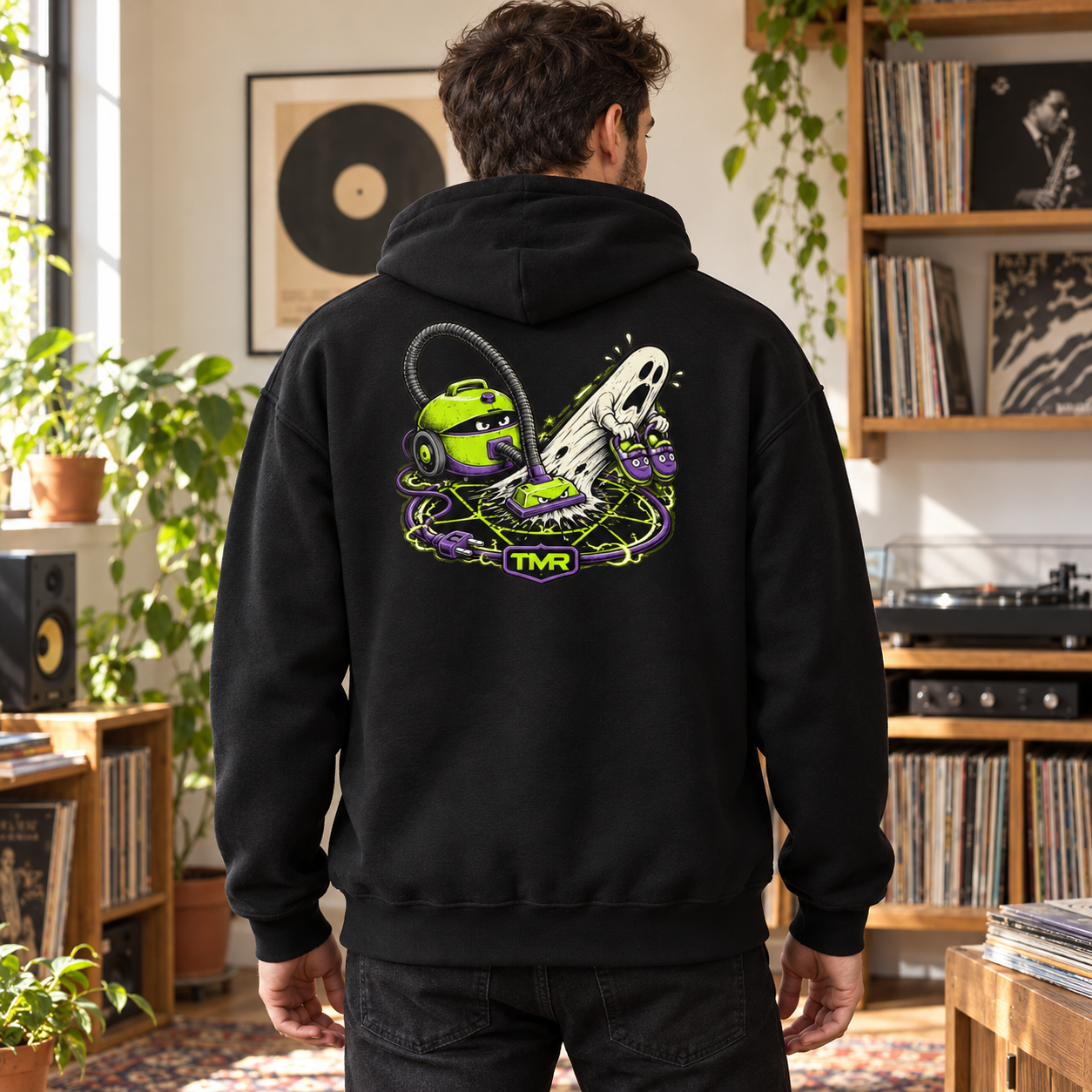 Cazafantasmas doméstico — Sudadera 1 Sudadera negra Cazafantasmas doméstico TMR by Tamar Melián, vista de espalda en un estudio de música luminoso con el estampado de aspiradora y fantasma