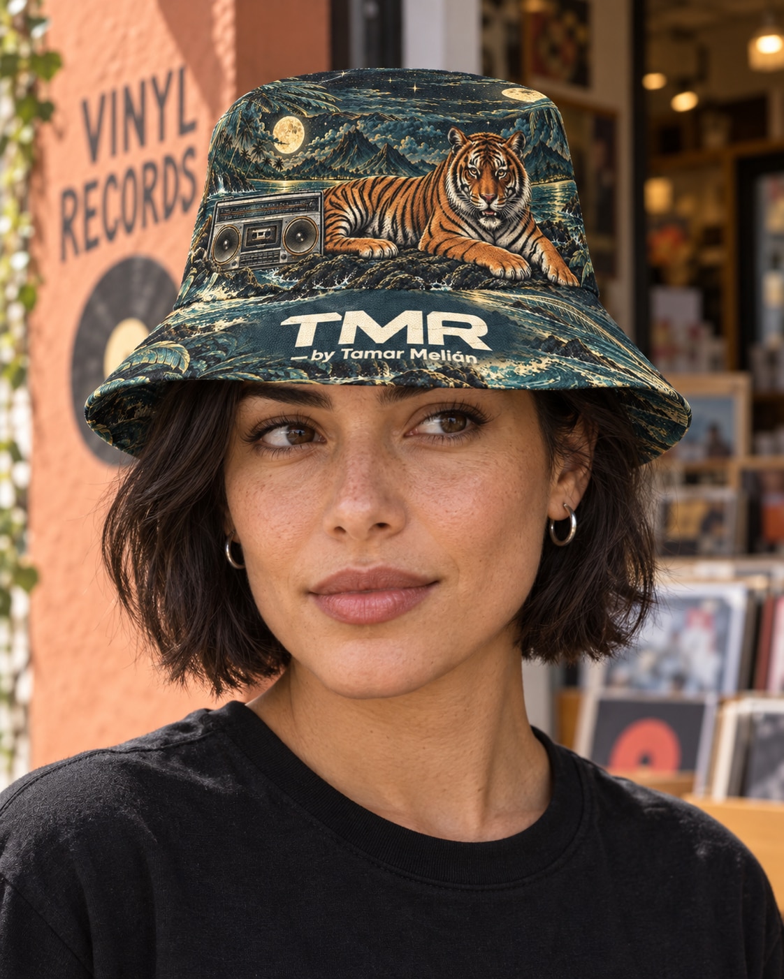 Gorro reversible Tigre Isla Magnética — TMR by Tamar Melián 2 Modelo adulta con el gorro TMR Tigre Isla Magnética en una tienda de vinilos; mockup digital