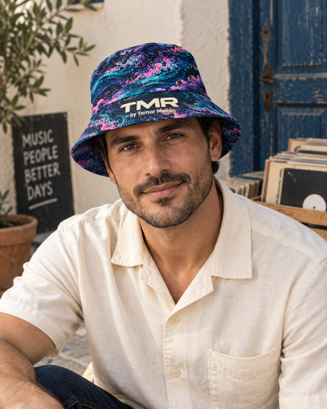 Gorro reversible Marea Eléctrica — TMR by Tamar Melián 3 Modelo adulto ficticio con el reverso de corrientes marinas del gorro Marea Eléctrica de TMR by Tamar Melián, junto a vinilos.