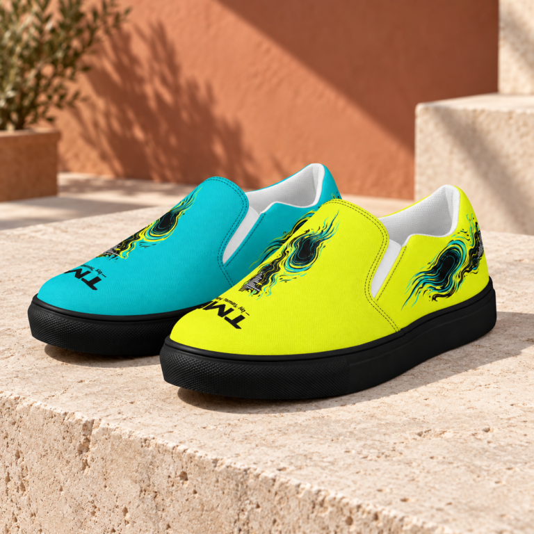 Par asimétrico Portal Runner Slip-on de TMR by Tamar Melián, amarillo y turquesa, sin cordones y con suela negra, sobre piedra clara.
