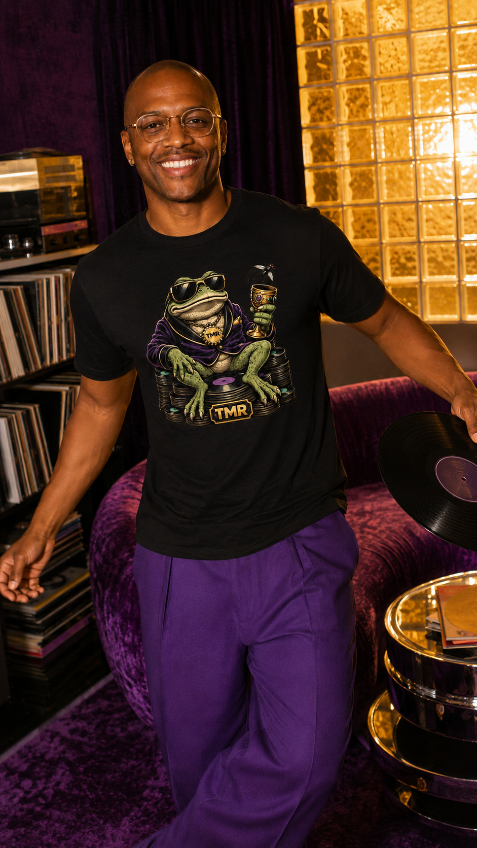 Sapo millonario — Camiseta 3 Mockup digital de un modelo adulto en una sala de vinilos con la camiseta negra Sapo millonario; el estampado frontal muestra un sapo con gafas, copa y discos.